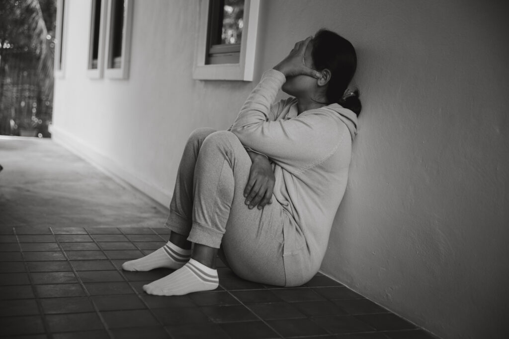Schizophrenia with lonely and sad in mental health depression concept. Depressed woman sitting against floor at home with dark room feeling miserable. Women are depressed, fearful and unhappy.
